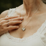 Woman wearing a silver heart shaped breastmilk filled pendant