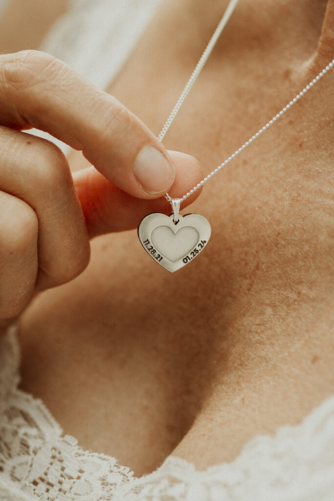 Woman wearing a silver heart shaped breastmilk filled pendant