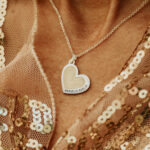 Woman wearing a silver heart shaped breastmilk filled pendant