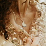 Woman wearing a silver heart shaped breastmilk filled pendant