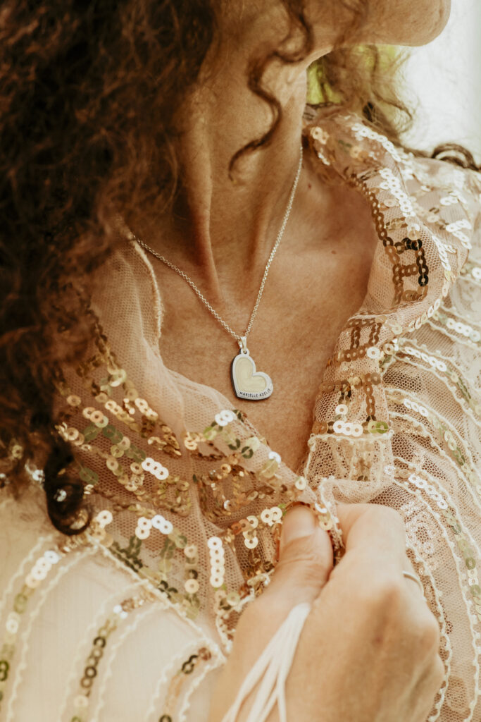 Woman wearing a silver heart shaped breastmilk filled pendant