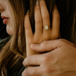 Woman wearing gold oval breastmilk filled ring