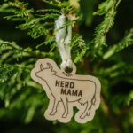 Wooden Christmas ornament with laser engraved cow hanging on a tree