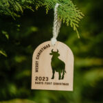 Wooden Christmas ornament with laser engraved cow hanging on a tree