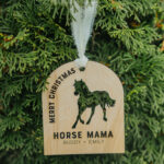 Wooden Christmas ornament with laser engraved horse hanging on a tree