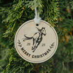 Wooden Christmas ornament with laser engraved horse hanging on a tree