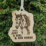 Wooden Christmas ornament with laser engraved horse and girl hanging on a tree