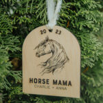 Wooden Christmas ornament with laser engraved horse hanging on a tree