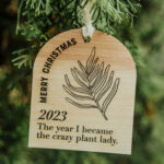 Wooden Christmas ornament with laser engraved plant hanging on a tree