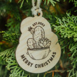 Wooden Christmas ornament with laser engraved cactus hanging on a tree