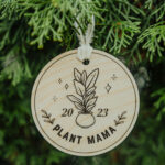 Wooden Christmas ornament with laser engraved plant hanging on a tree