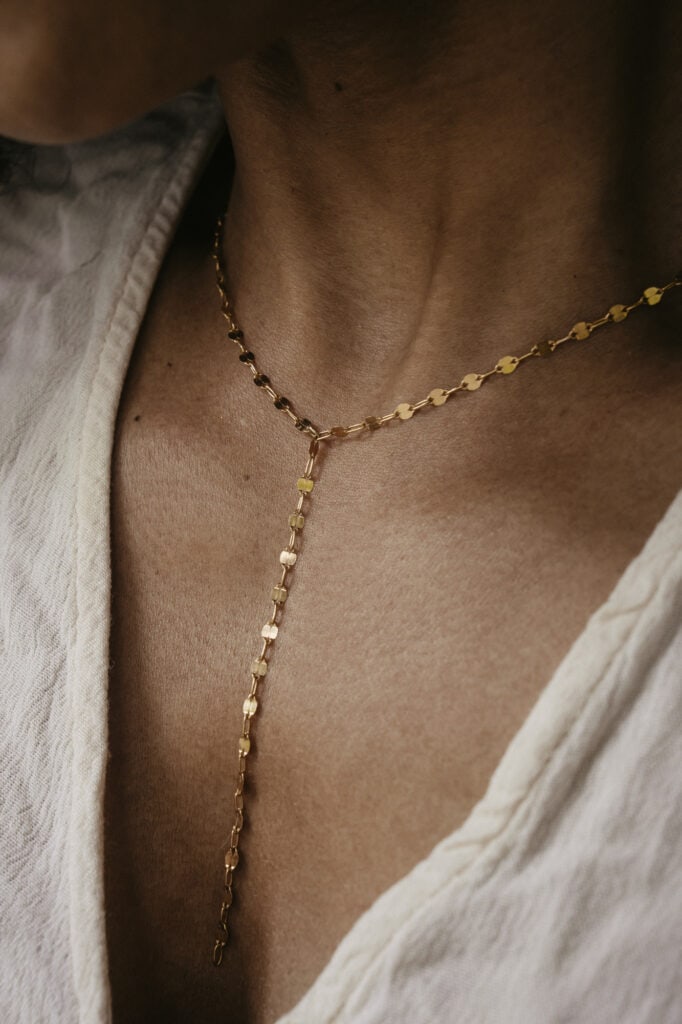 Close-up of a gold necklace with a delicate chain and pendant on a woman's neck.