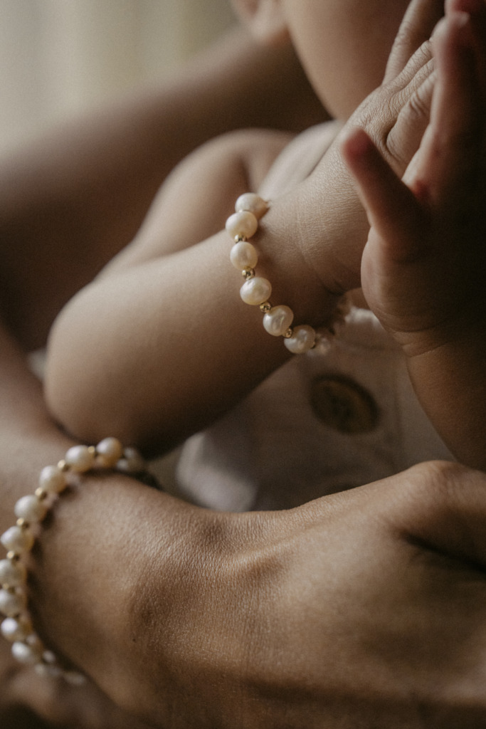 Close-up of a baby's wrist with a pearl bracelet and gold beads for a first pearl jewelry gift.